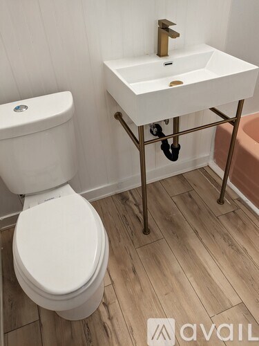 A white toilet sits next to a white sink on a stand in a bathroom.