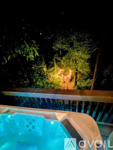 A hot tub on a balcony with a view of a garden at night.