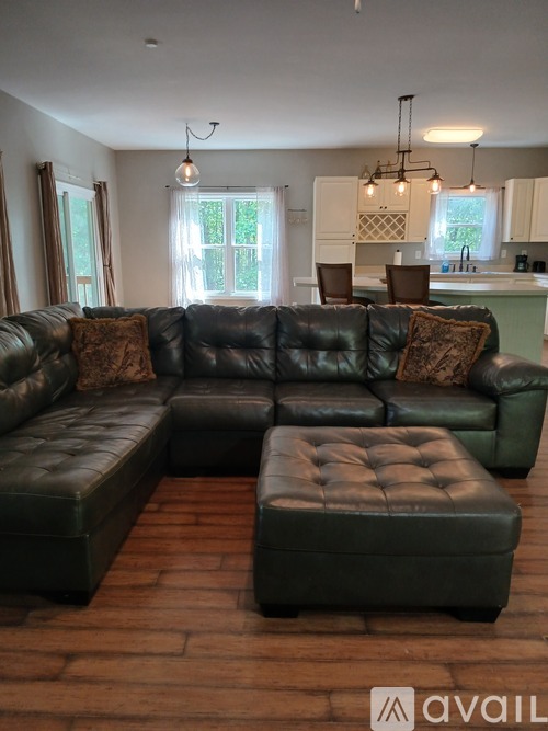 A black leather sectional sofa with a chaise lounge and ottoman in a living room.