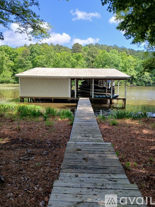 A wooden walkway leads to a white house on a lake.