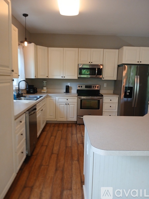 A kitchen with white cabinets and a wooden floor.