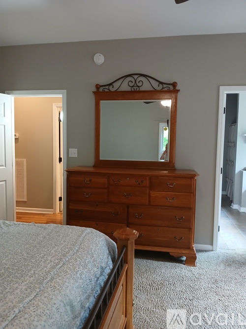 A bedroom with a bed, dresser and mirror.