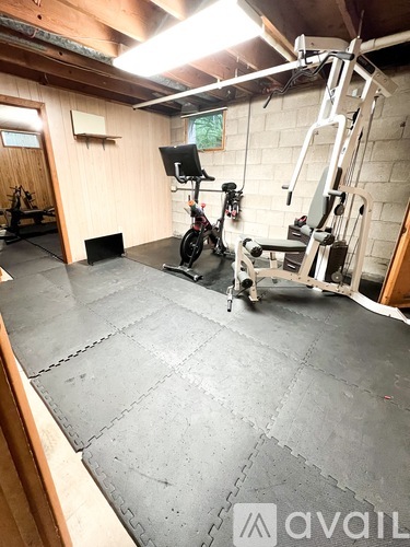 A gym with a treadmill, weights and a television.