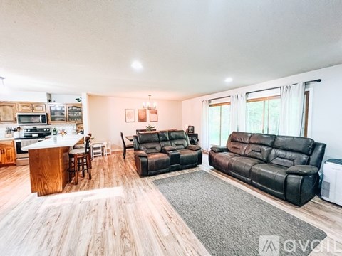A living room with black leather furniture and a wooden bar area.