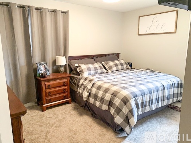 A bedroom with a bed, nightstand, and curtains.