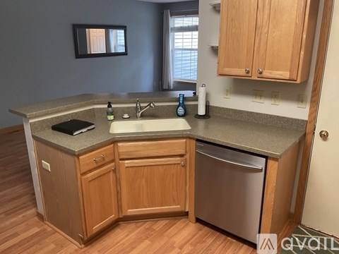 A kitchen with wooden cabinets and a stainless steel dishwasher.