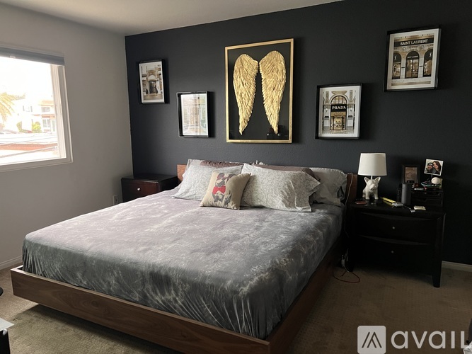 A bedroom with a bed, nightstand, and pictures on the wall.