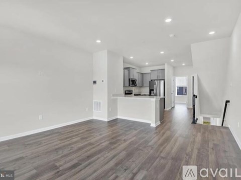 A spacious living room with wood flooring and white walls.