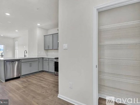 A kitchen with white cabinets and a wooden floor.