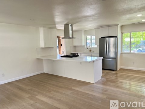 A kitchen with white cabinets and a wooden floor.