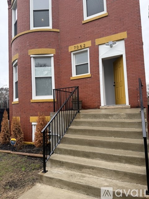 A red brick building with a yellow door and windows.