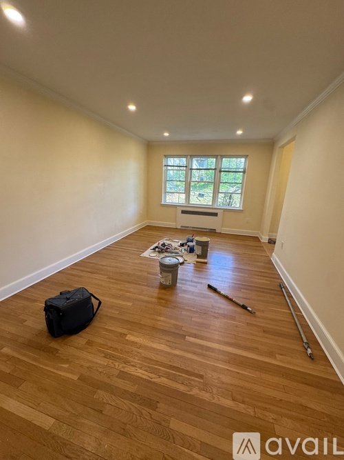 A room with wooden flooring and a window is being prepared for painting.