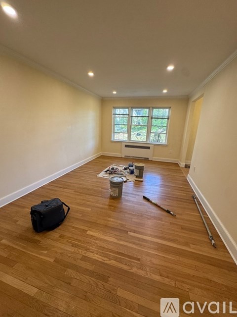A room with wooden flooring and a window is being prepared for painting.