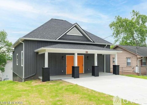 A modern house with a grey exterior and orange doors.