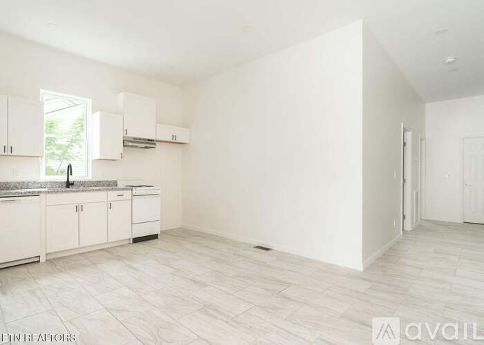 A spacious kitchen with white cabinets and a marble countertop.