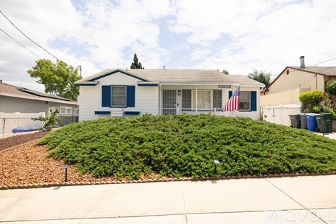 A house with a blue and white exterior and a flag on the front.