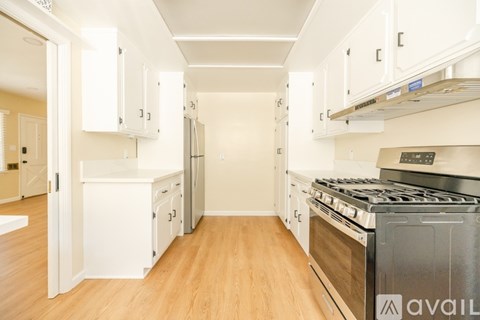 A kitchen with white cabinets and a stove top oven.