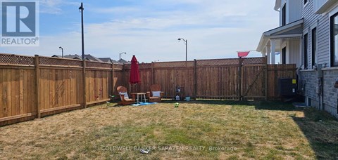 A backyard with a wooden fence and a red umbrella.