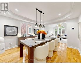A modern dining room with a wooden table and white chairs.