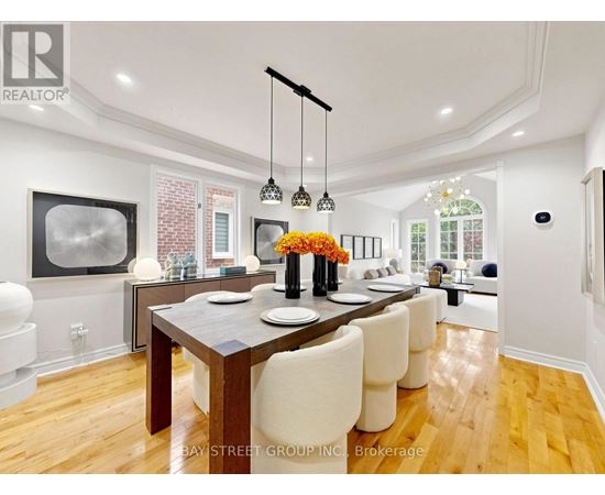 A modern dining room with a wooden table and white chairs.