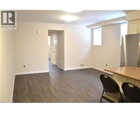 A room with a wooden floor and a refrigerator in the corner.