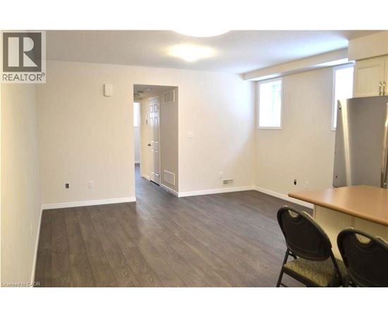 A room with a wooden floor and a refrigerator in the corner.