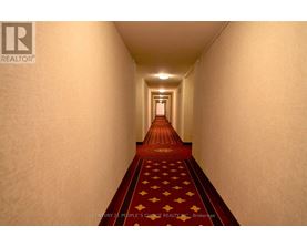 A hallway with a red carpet and a logo on the wall.