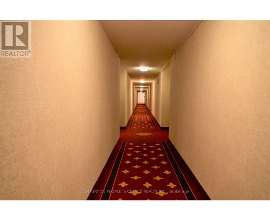 A hallway with a red carpet and a logo on the wall.