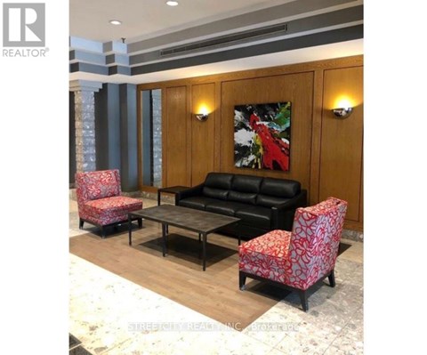 A living room with a black couch, two red patterned chairs, and a coffee table.