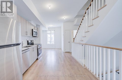 A spacious kitchen with white cabinets and a staircase with white railings.