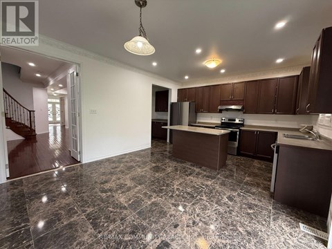 A kitchen with brown cabinets and a marble floor.