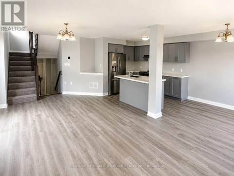 A spacious kitchen and living room with wood flooring and a staircase.