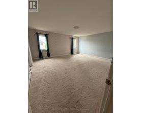 A room with a carpeted floor and a window with curtains.