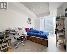 A bedroom with a bed, desk, and chair.