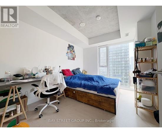 A bedroom with a bed, desk, and chair.