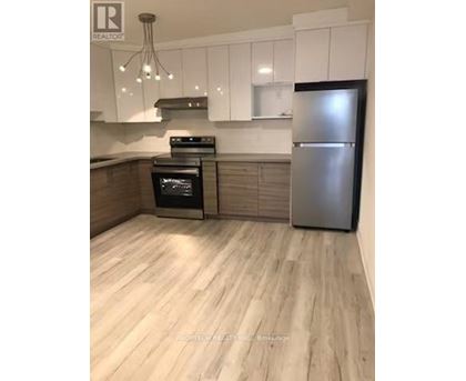 A kitchen with a stainless steel refrigerator and wooden flooring.
