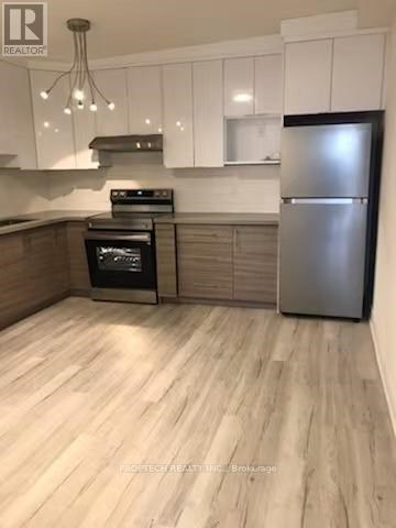 A kitchen with a stainless steel refrigerator and wooden flooring.