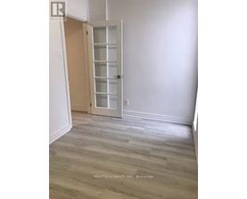 A room with a white door and wooden flooring.