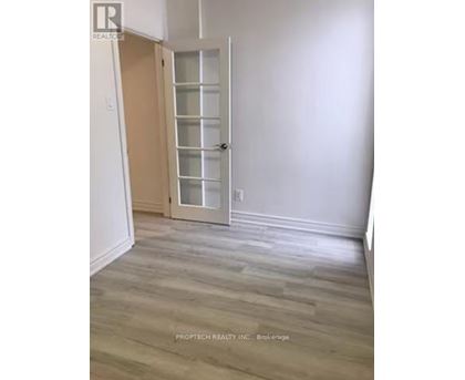 A room with a white door and wooden flooring.
