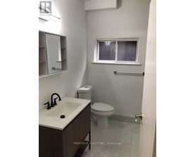 A white bathroom with a sink, toilet and a window.