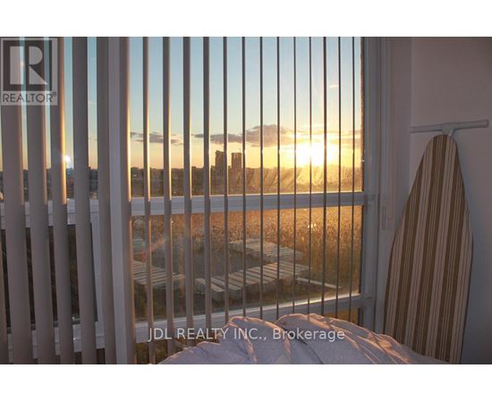 A sunset view from a window with a towel hanging on a hook.