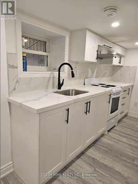 A white kitchen with a sink and a window.