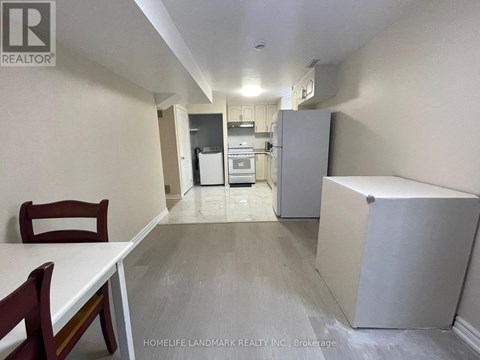 A kitchen with a table and chairs in the foreground and a refrigerator in the background.