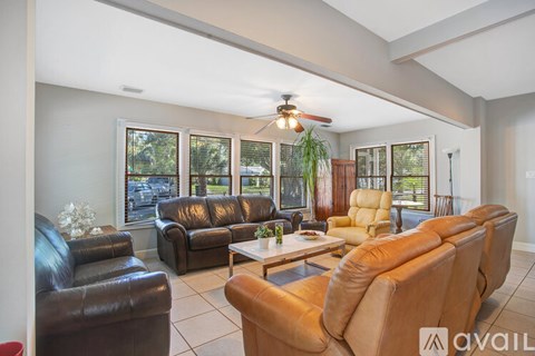 A living room with a row of leather couches and a ceiling fan.