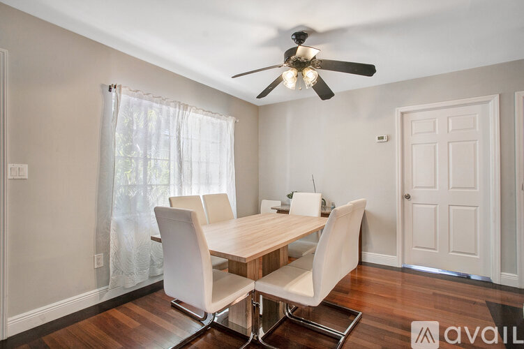 A dining room with a table and chairs and a ceiling fan.