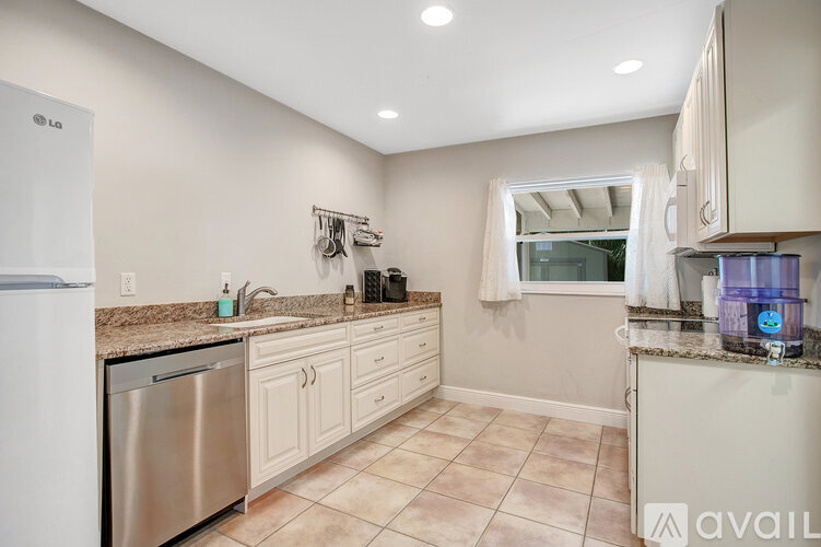 A kitchen with a stainless steel dishwasher and white appliances.