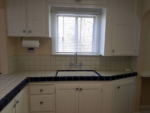 A kitchen with white cabinets and a black and white tiled backsplash.