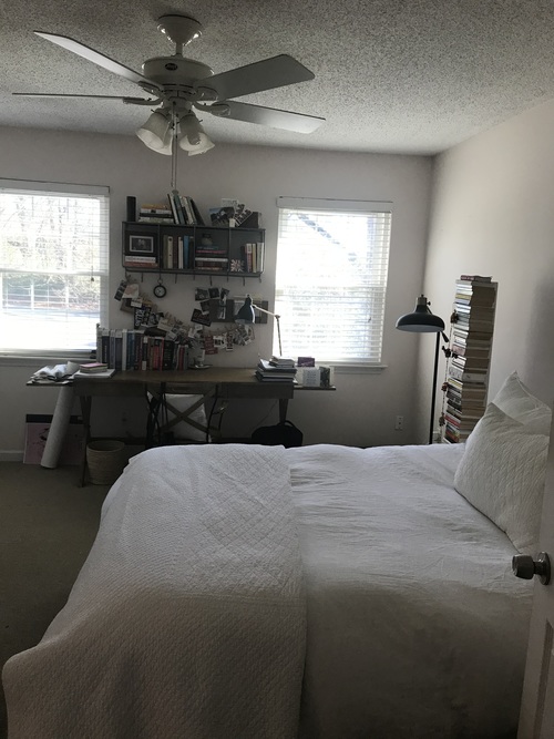 A bedroom with a bed, desk, and ceiling fan.