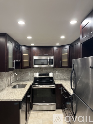 A modern kitchen with dark wood cabinets and stainless steel appliances.