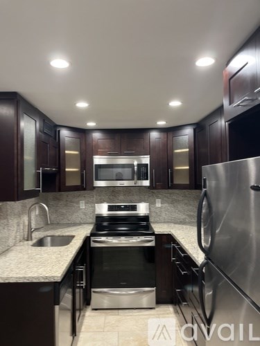 A modern kitchen with dark wood cabinets and stainless steel appliances.